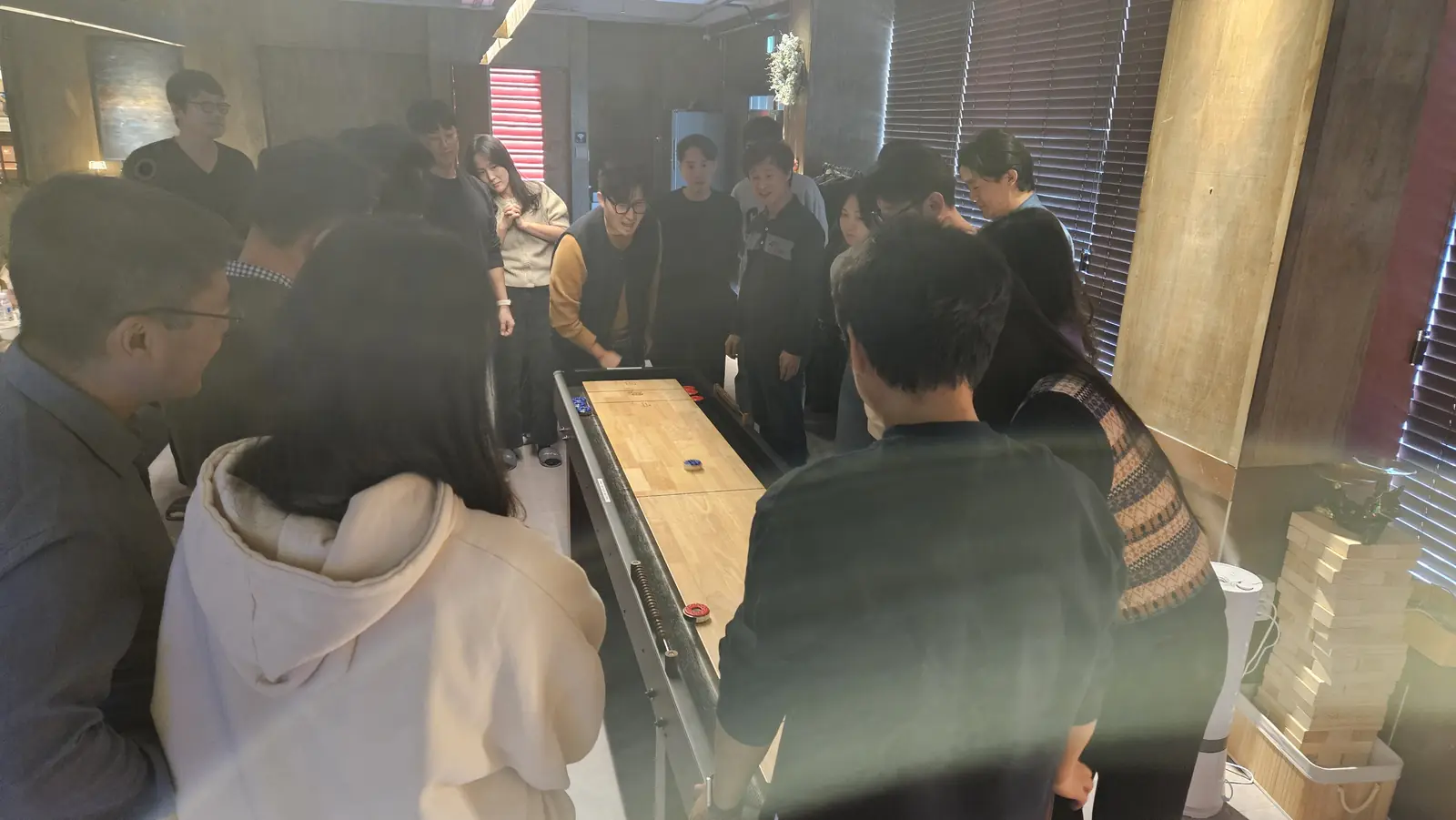 화랑에서 컬링 테이블 주위에 모인 기업 워크숍 참가자들