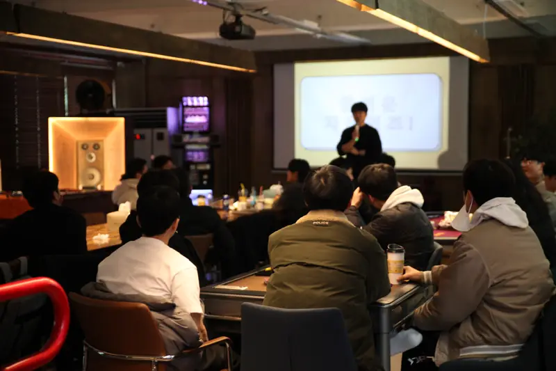 큰 스크린 앞에 모여 준비해온 퀴즈를 즐기는 참가자들
